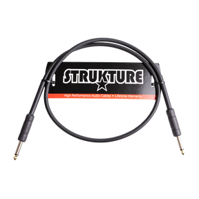 The image shows a STRUKTURE brand high-performance audio cable with 1/4" jack connectors on both ends, designed for musical instruments. The black cable features a lifetime warranty label on its packaging and is likely a short instrument or patch cable used for connecting guitars, basses, keyboards, and audio equipment in live or studio settings.