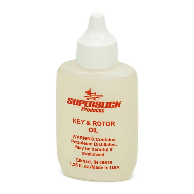 The image shows a small bottle of "Key & Rotor Oil" by Superslick Products, a lubricant for brass and woodwind instruments. It is designed to oil keys, rotors, and moving parts on instruments like trumpets, French horns, trombones, saxophones, and clarinets. The 1.25 fl. oz. squeeze bottle has a dispensing tip for precise application, helping keep instrument mechanisms smooth and preventing sticking or corrosion.