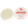 The image shows a container of Superslick Tuning Slide Grease, a specialized lubricant for brass instruments like trumpets, trombones, and tubas. The small white plastic jar with a red-labeled lid is open to reveal cream-colored grease inside. Made in Elkhart, Indiana, it helps tuning slides move smoothly for proper pitch adjustment, preventing sticking and ensuring the instrument stays in good condition.