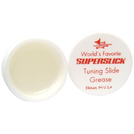 The image shows a container of Superslick Tuning Slide Grease, a specialized lubricant for brass instruments like trumpets, trombones, and tubas. The small white plastic jar with a red-labeled lid is open to reveal cream-colored grease inside. Made in Elkhart, Indiana, it helps tuning slides move smoothly for proper pitch adjustment, preventing sticking and ensuring the instrument stays in good condition.