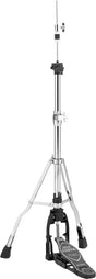 The image shows a chrome hi-hat cymbal stand with a tripod base, adjustable legs, and a tall vertical shaft. At the top is a clutch mechanism for holding two cymbals (not visible). A foot pedal at the base controls opening and closing of the cymbals. The stand features black hardware, adjustable height, and sturdy construction, making it an essential, stable component of a drum kit for versatile playing with sticks and foot control.