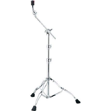 The image shows a chrome cymbal boom stand with a tripod base featuring rubber feet for stability. It has a telescoping main post for height adjustment and an angled boom arm to position cymbals at various angles and distances. Multiple wing nut clamps secure adjustments, and a cymbal holder with a felt washer tops the stand. This stand is used to place cymbals precisely in drum kits without obstructing the drummer.