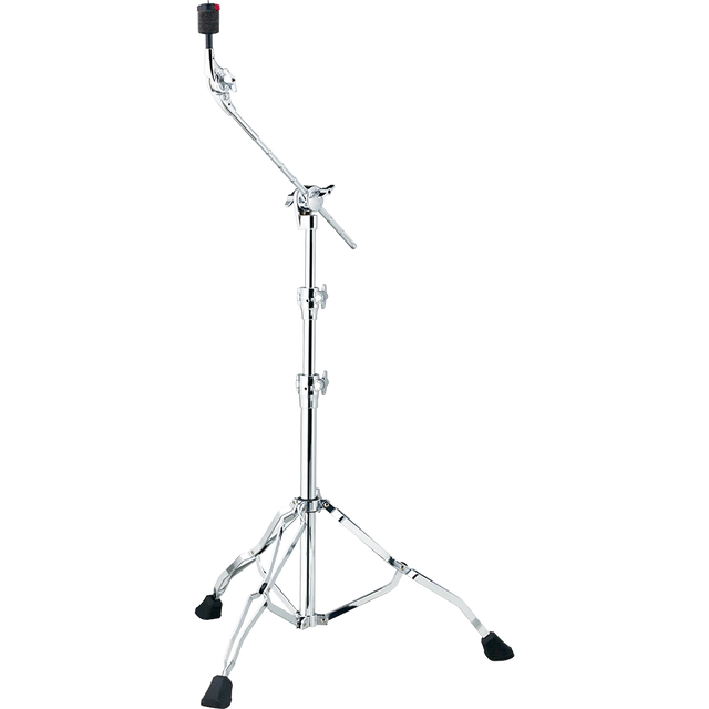 The image shows a chrome cymbal boom stand with a tripod base featuring rubber feet for stability. It has a telescoping main post for height adjustment and an angled boom arm to position cymbals at various angles and distances. Multiple wing nut clamps secure adjustments, and a cymbal holder with a felt washer tops the stand. This stand is used to place cymbals precisely in drum kits without obstructing the drummer.
