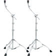The image shows a pair of professional chrome-plated boom cymbal stands with sturdy tripod bases and rubber feet for stability. Each stand has adjustable height sections, angled boom arms for flexible positioning, wing nuts for securing adjustments, and cymbal felts at the top for mounting cymbals. These stands help drummers position cymbals at desired heights and angles, especially in tight drum kit setups.