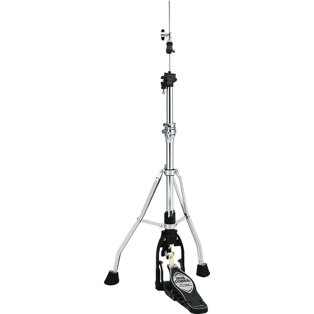 The image shows a hi-hat cymbal stand with a tall, adjustable chrome post, sturdy tripod base with rubber feet, and a black foot pedal featuring a brand logo. It includes clamps and adjustment mechanisms along the post. This essential drum hardware holds hi-hat cymbals (not shown) and allows drummers to control cymbal tension and create varied sounds from tight "chick" to open crashes.