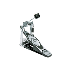 The image shows a Tama Iron Cobra 200 series bass drum pedal, featuring the distinctive branding on the footplate and Tama logo. It has a chain-drive mechanism, adjustable beater with a black rubber/felt head, and a spring return. The pedal is made of sturdy metal with a silver, chrome, and black finish. Known for reliability and smooth operation, it’s an intermediate-level pedal suitable for practice and performance.