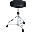 The image shows a Tama "1st Chair" drum throne with a round, padded black seat and visible branding. It features a height-adjustable threaded post, a chrome-plated tripod base with three legs, and black rubber feet for stability and floor protection. This professional-grade drum stool is essential for drummer comfort, posture, and performance.