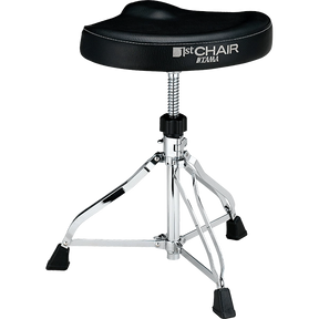 The image shows a Tama "1st CHAIR" drum throne featuring a black padded vinyl seat with ergonomic design, chrome tripod legs with rubber feet, and an adjustable height mechanism with a locking post. The sturdy, professional-grade construction and visible Tama branding highlight its role in providing drummers with stable, comfortable seating for optimal posture and performance during extended playing sessions.