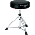 The image shows a Tama drum throne from the "1st Chair" series with a round, padded black vinyl seat. It features an adjustable height threaded rod, a sturdy chrome tripod base with rubber feet for stability, and professional-grade construction. This durable stool provides comfort and optimal seating for drummers during long sessions, reflecting Tama’s reputation for high-quality percussion accessories.