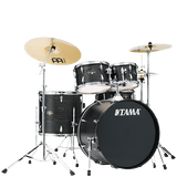 The image shows a complete Tama acoustic drum kit with a bass drum, snare, multiple tom-toms, and a floor tom. It includes chrome hardware, pedals, and two Meinl cymbals (a larger crash/ride on the left and a smaller cymbal on the right). The drums have a dark wood grain or black finish. This versatile setup is suitable for various musical styles like rock, jazz, and pop.
