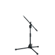 The image shows a professional black microphone stand with a tripod base and an adjustable boom arm. It has multiple height and angle adjustment points with locking mechanisms for stability. This versatile stand is commonly used by musicians, vocalists, and audio engineers to position microphones for recording, live performances, and studio work.