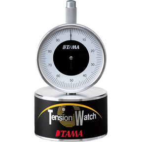 The image shows a Tama Tension Watch, a precision drum tuning tool with a 0-100 gauge dial and chrome construction. It measures drumhead tension for consistent tuning, featuring a circular base labeled "Tension Watch" and Tama branding. Ideal for drummers and technicians, it ensures even tension for studio, live, and professional use. Tama is a respected Japanese drum maker known for quality accessories.