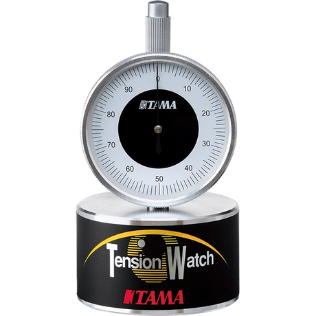 The image shows a Tama Tension Watch, a precision drum tuning tool with a 0-100 gauge dial and chrome construction. It measures drumhead tension for consistent tuning, featuring a circular base labeled "Tension Watch" and Tama branding. Ideal for drummers and technicians, it ensures even tension for studio, live, and professional use. Tama is a respected Japanese drum maker known for quality accessories.