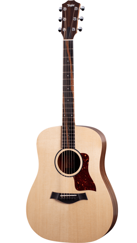 The image shows a Taylor acoustic guitar with a natural wood finish and classic dreadnought shape. It features six tuning pegs, a tortoiseshell pickguard, a black bridge with a compensated saddle, and a rosewood or ebony fretboard with dot markers. The headstock displays the Taylor logo. The guitar is photographed against a white background, showcasing Taylor's clean design and quality craftsmanship.