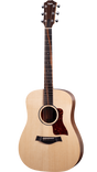 The image shows a Taylor acoustic guitar with a natural wood finish and classic dreadnought shape. It features six tuning pegs, a tortoiseshell pickguard, a black bridge with a compensated saddle, and a rosewood or ebony fretboard with dot markers. The headstock displays the Taylor logo. The guitar is photographed against a white background, showcasing Taylor's clean design and quality craftsmanship.