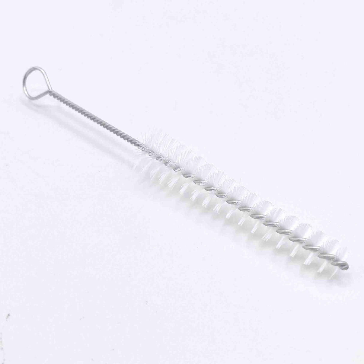 The image shows a cleaning brush for musical instruments, featuring a long, flexible wire handle with a hanging loop and white cylindrical bristles. Its slender design is ideal for cleaning narrow tubes and bores of wind, brass, and woodwind instruments like flutes, clarinets, trumpets, and saxophones. This essential tool helps remove moisture and debris to maintain sound quality and instrument longevity.